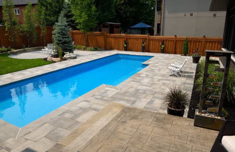 Completed landscaping around new swimming lap pool in back yard with paver patios gardens and lawn Barrie Ontario Canada